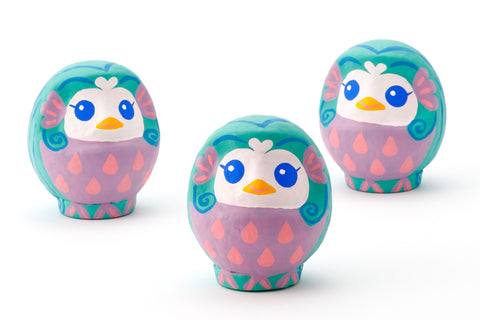 Three Imai Daruma Naya Amabie-sama, lucky creature papier-mache Japanese dolls. Each one has a purple stomach with pink scales, a turquoise head and white face, featuring blue eyes and yellow beak.