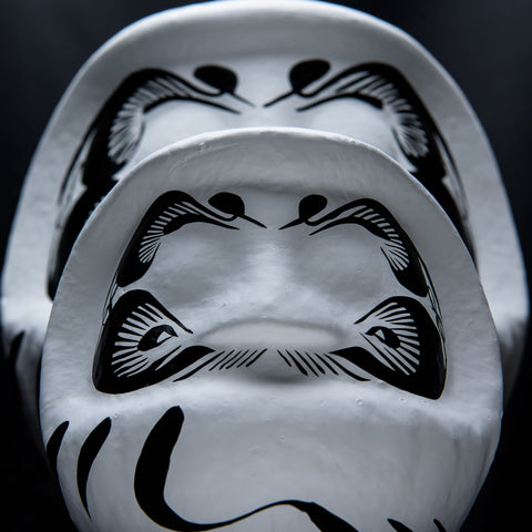Two large white Imai Daruma Naya Designer’s Daruma Japanese papier-mache dolls, featuring a pattern of white eyebrows and beard and a three swirl lines across its body.