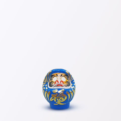 A 9-centimeter tall blue Fuku-iri lucky daruma doll, made by Imai Daruma Naya, featuring a rotund body and decorative patterns for eyebrows and beard and gold body lines and kanji lettering.