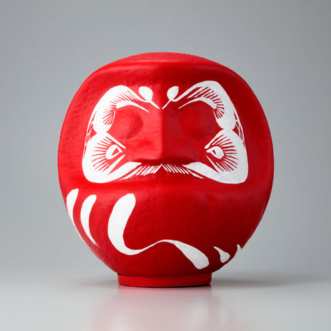 A large red Imai Daruma Naya Designer’s Daruma Japanese papier-mache doll, featuring a pattern of white eyebrows and beard and a three swirl lines across its body.
