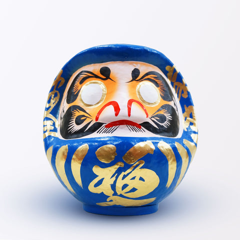 A 20-centimeter tall blue Fuku-iri lucky daruma doll, made by Imai Daruma Naya, featuring a rotund body and decorative patterns for eyebrows and beard and gold body lines and kanji lettering.