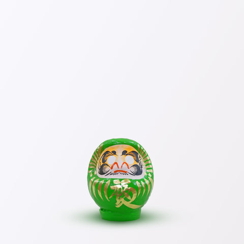 A 9-centimeter tall green Fuku-iri lucky daruma doll, made by Imai Daruma Naya, featuring a rotund body and decorative patterns for eyebrows and beard and gold body lines and kanji lettering.