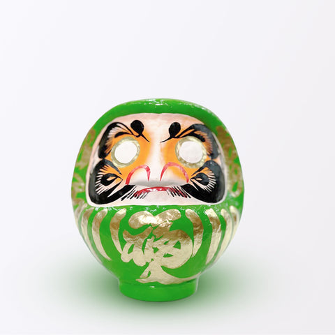 A 17-centimeter tall green Fuku-iri lucky daruma doll, made by Imai Daruma Naya, featuring a rotund body and decorative patterns for eyebrows and beard and gold body lines and kanji lettering.