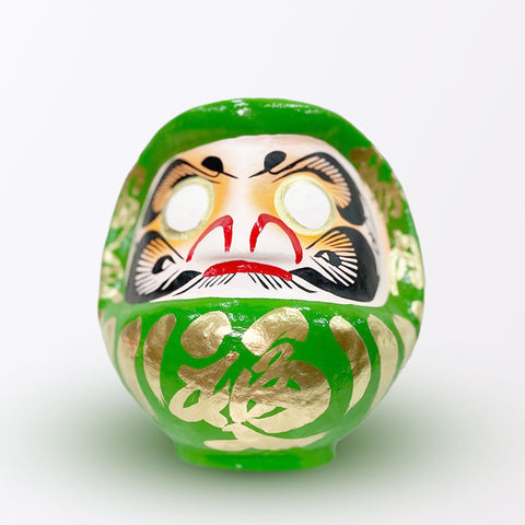 A 20-centimeter tall green Fuku-iri lucky daruma doll, made by Imai Daruma Naya, featuring a rotund body and decorative patterns for eyebrows and beard and gold body lines and kanji lettering.