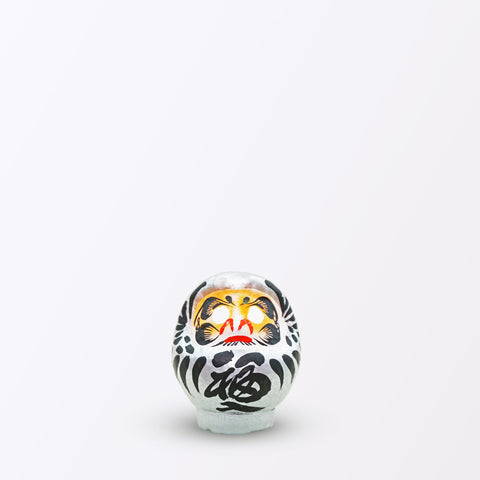 A 9-centimeter silver Fuku-iri papier-mache daruma dolls, made by Imai Daruma Naya. All feature rotund bodies, decorative patterns for eyebrows and beards and black body lines and kanji lettering.