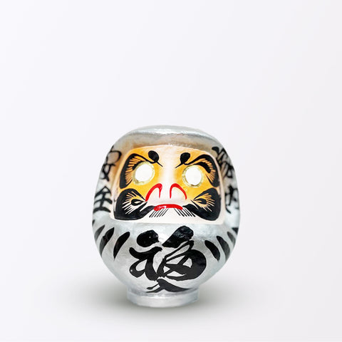 A 15-centimeter tall silver Fuku-iri papier-mache daruma dolls, made by Imai Daruma Naya. All feature rotund bodies, decorative patterns for eyebrows and beards and black body lines and kanji lettering.