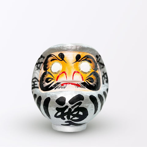 A 17-centimeter tall silver Fuku-iri papier-mache daruma dolls, made by Imai Daruma Naya. All feature rotund bodies, decorative patterns for eyebrows and beards and black body lines and kanji lettering.