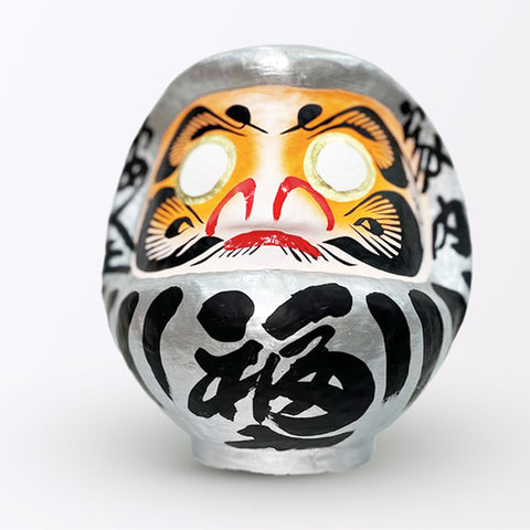 A 23-centimeter tall silver Fuku-iri papier-mache daruma dolls, made by Imai Daruma Naya. All feature rotund bodies, decorative patterns for eyebrows and beards and black body lines and kanji lettering.