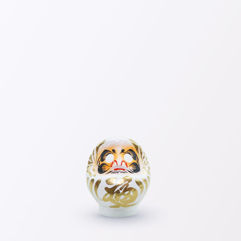 A 9-centimeter tall white Fuku-iri papier-mache daruma dolls, made by Imai Daruma Naya. All feature rotund bodies, decorative patterns for eyebrows and beards and gold body lines and kanji lettering.