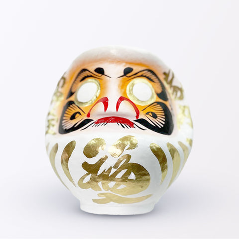 A 20-centimeter tall white Fuku-iri papier-mache daruma dolls, made by Imai Daruma Naya. All feature rotund bodies, decorative patterns for eyebrows and beards and gold body lines and kanji lettering.