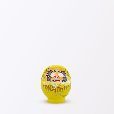 A 9-centimeter yellow Fuku-iri papier-mache daruma dolls, made by Imai Daruma Naya. All feature rotund bodies, decorative patterns for eyebrows and beards and gold body lines and kanji lettering.