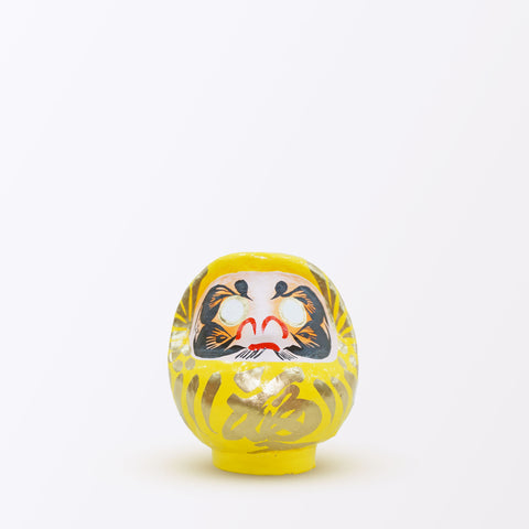 A 12-centimeter tall yellow Fuku-iri papier-mache daruma dolls, made by Imai Daruma Naya. All feature rotund bodies, decorative patterns for eyebrows and beards and gold body lines and kanji lettering.