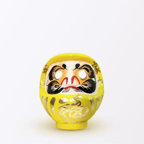 A 15-centimeter tall yellow Fuku-iri papier-mache daruma dolls, made by Imai Daruma Naya. All feature rotund bodies, decorative patterns for eyebrows and beards and gold body lines and kanji lettering.